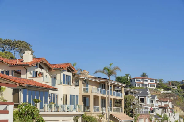 Houses with glass railings on decks at San Clemente, California. Neighborhood with view decks near the mountain with building on top against the clear sky background.