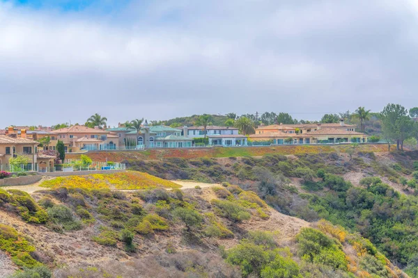 Suburban houses with glass fence at the edge of the mountain slope at Laguna Niguel. Uphill residential area in Southern California.