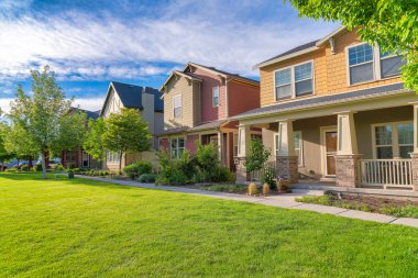 Quiet neighborhood with large houses at Daybreak, Utah. Facade of houses with traditional designs with gable porches and sidings made of wood and shingle materials.