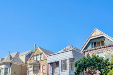 Roof structures of houses in San Francisco, California. Low angle view of houses with victorian style structures and gable roofs against the clear blue sky background.