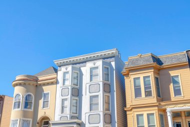 Three houses with different designs and colors in San Francisco, California. There is a house on the left with curved walls beside the house with bow windows near the house with vinyl lap sidings.