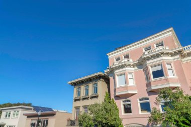Resdidential buildings in a low angle view against the clear blue sky. Neighborhood in San Francisco, California with large building structures and solar panel on roof.