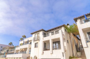 Exterior of residential buildings at San Clemente, California with balconies. There is a staircase in the middle of the buildings on the right with trees on the side and a view of the sky at the back.
