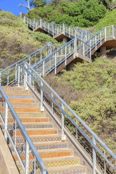 Outdoor stairs with metal railings on a mountain at San Clemente, California. Staircase on a mountain slope with shrubs and trees.