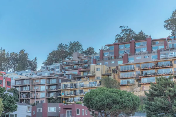 Sloped apartment buildings with terrace in San Francisco, California. Facade of apartment buildings with floor to ceiling windows and balconies against the clear sky.