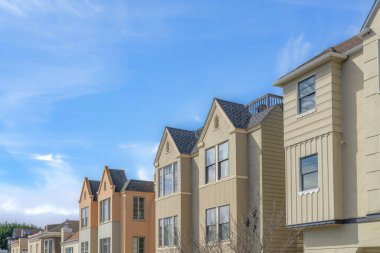 Townhouses in the suburban neighborhood in San Francisco, California with diffrent exterior. Row of townhouses with bow windows against the sky.