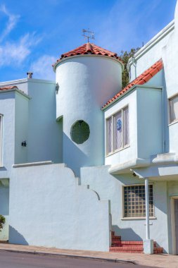 Facade of a gray mediterranean style house with concrete tile roofs. Exterior of a house with bricks on the stairs at the front near the pillar and window.