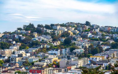 Rows of townhouses and apartment buildings on a sloped land in San Francisco, California. High angle view of a suburban community with white sky background.