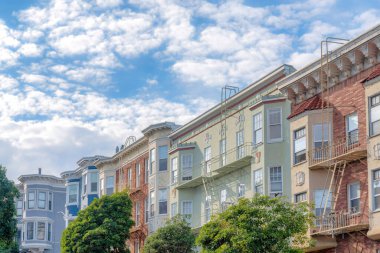 Houses at the suburbs community of San Francisco, California with emergency stairs outdoors. Residential buildings with bricks and painted walls with a view of clouds at the sky.