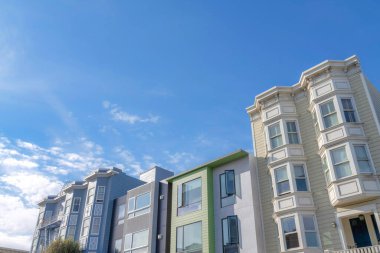 Complex townhomes with traditional and moderndesign in a low angle view. Neighborhood in San Francisco, California with townhomes with modern designs in the middle of two townhouses with bay windows.