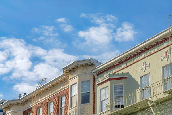 Slanted view of flat roofs of complex residential buildings with emergency staircase. Neighborhood in San Francisco, California with painted tiles and bricks wall claddings in a low angle view.