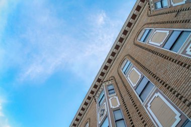 Low angle view of a georgian style residential buildings with brown bricks in San Francisco, CA. Tall building structure with ornate trims and single hung windows against the sky view background.