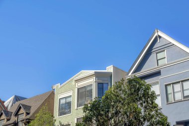 Suburban houses with different architectural designs and structures in San Francisco, California. There is a house on the right with gray stucco wall beside the houses with wood shingles sidings.