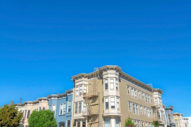Apartment building along the complex townhouses in San Francisco, California. There is an apartment building at the front with two emergency stairs outside beside the townhouses on its sides.