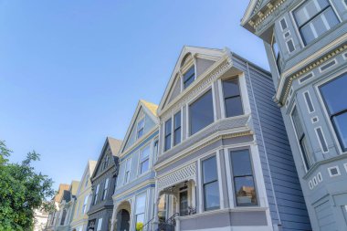 Row houses with victorian facade exterior in San Francisco, California. Low angle view of houses with gable roofs and decorative trim details.