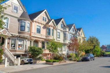 Complex houses with basement garages and stairs at the front in San Francisco, California. There is a house on the left with holloween ornaments and parked car at the front.