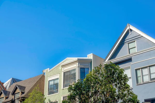 Suburban houses with different architectural designs and structures in San Francisco, California. There is a house on the right with gray stucco wall beside the houses with wood shingles sidings.