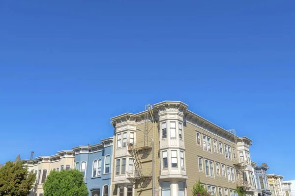 Apartment building along the complex townhouses in San Francisco, California. There is an apartment building at the front with two emergency stairs outside beside the townhouses on its sides.