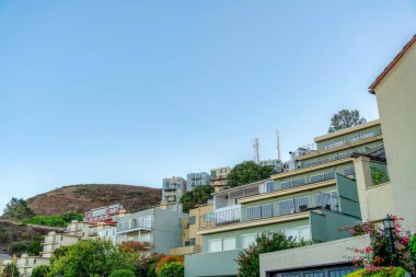 Multi-storey apartment buildings near the hill in San Francisco, California. Facade of apartment buildings with balconies and a view of the hill at the back against the sky.