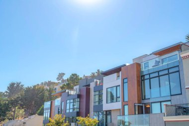 Modern townhouses with large glass windows and wood wall cladding in San Francisco, California. Modern townhouses with daylighting structure and roof decks in a sloped neighborhood.