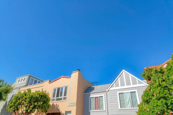 Facade of single-family houses with traditional design and mediterranean style exterior. Houses in a low angle view at San Francisco, California against the clear blue sky.