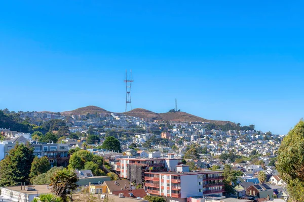 High angle view of a neighborhood with dense residential buildings near the cell tower on a mountain. There are apartment buildings and single-family homes the suburbs of San Francisco, CA.