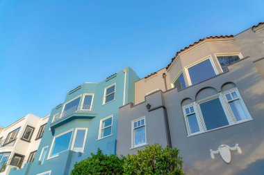 Painted three large houses in San Francisco, California. There are three houses, on the left is with white exterior and balconies near the blue house at the center and gray house on the right.