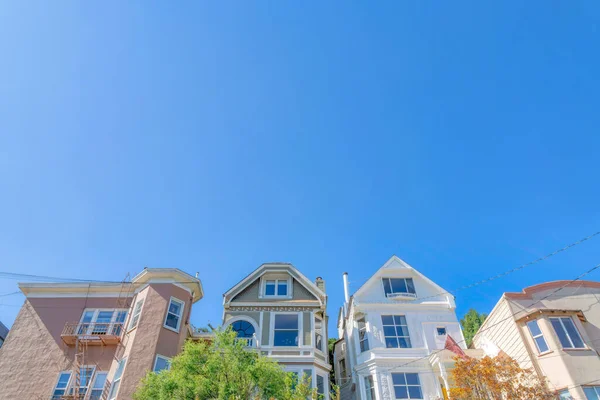 Low angle view of middle class houses against the clear sky at San Francisco, California. Four large houses with painted stucco walls and there is a house on the left with emergency stairs.