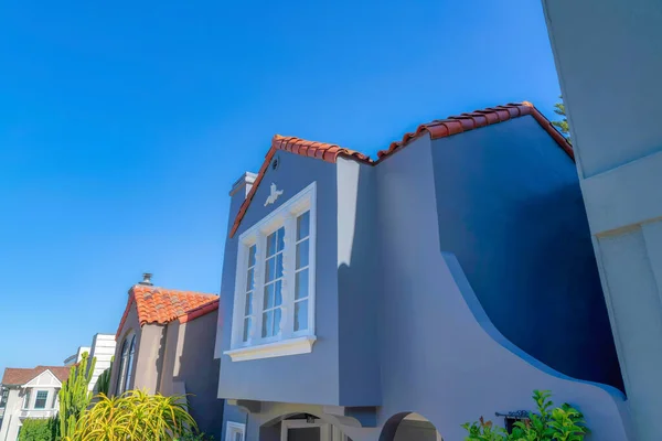 Row of houses with concrete tile roofs against the clear blue sky at San Francisco, California. There is a house at the front with white trims and a view of cactus along the plants on the left.