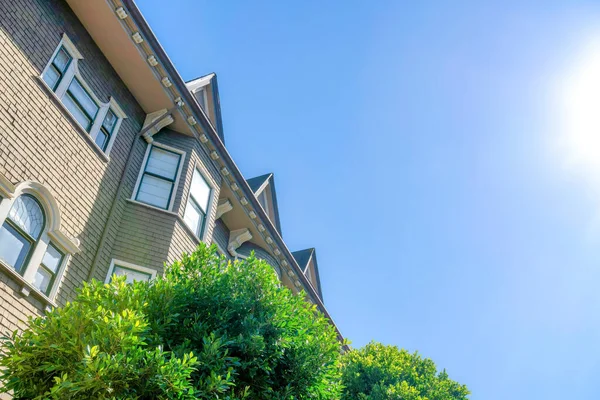 Low angle view of a french country style building against the clear sky at San Francisco, CA. There are trees at the front of a residential building with wood shingle siding and decorative trims.