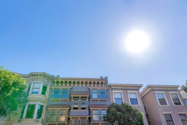Afternoon sun hovering over the victorian houses at San Francisco, California. There are rows of victorian houses with decorative trims.