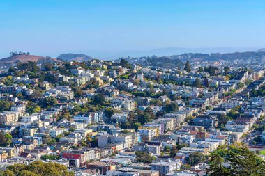 Dense residential buildings view from above in San Francisco, California. There are apartments and large single-family homes near the hill on the left.