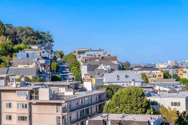 Above view of a residential area in San Francisco, California. There are apartment buildings and single-family houses with street and columnar trees in the middle.