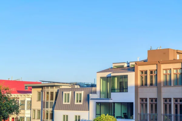 Row of traditional and modern house buildings at San Francisco, California. Facade of houses with picture windows against the clear sunset sky background.