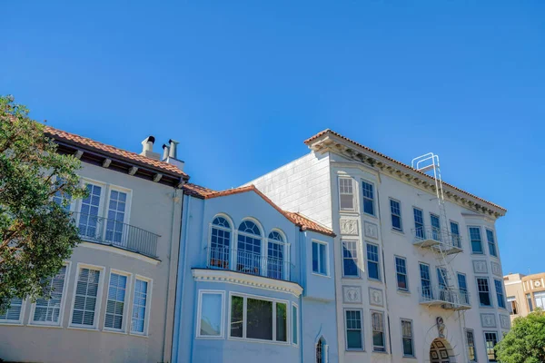 Two single family houses along with an apartment building with emergency stairs in San Francisco, CA. Exterior of three residential buildings with two houses on the left and apartment on the right.