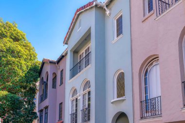 Row of mediterrenean houses in San Francisco, California. Exterior of houses with painted stucco wall and railings at the front of its arched windows.