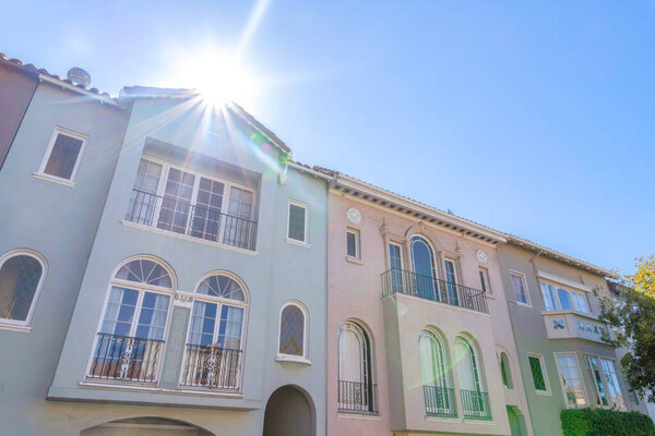 Sun above the row of mediterranean adjacent houses at San Francisco, California. Facade of three-storey houses with window railings and balconies.