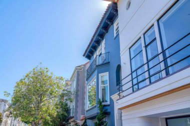 Row of modern mediterranean homes in a neighborhood at San Francisco, California. There are trees near the front of the houses with different exterior designs.