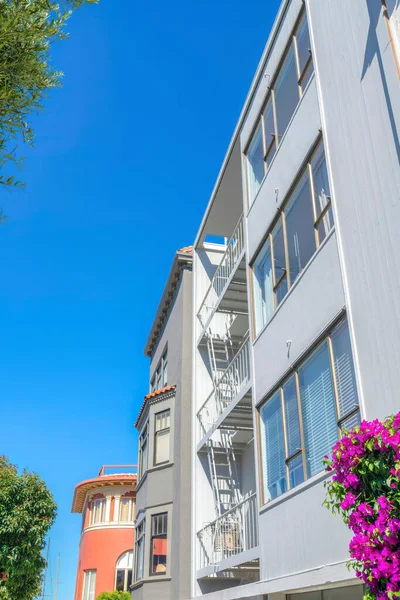 Modern low-rise apartment buildings in a low angle view at San Francisco, CA. There is a modern building at the front with emergency stairs along with the mediterranean buildings at the back.