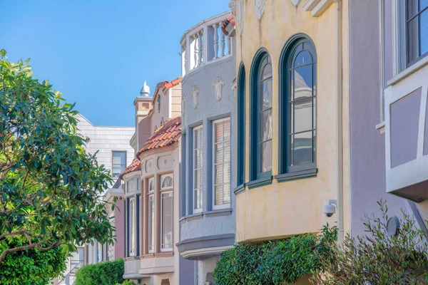 Decorative window exterior of adjacent homes at San Francisco, California. Side view of row of houses with mediterranean exterior and trees outdoors.