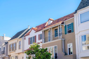 Adjacent homes in a neighborhood in San Francisco, California. Row of houses with different architectural exterior and fake window shutters.