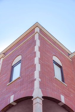 Corner exterior of a building with bricks and quoin in San Francico, California. Building exterior in a low angle view with red bricks and windows with glass and arches.