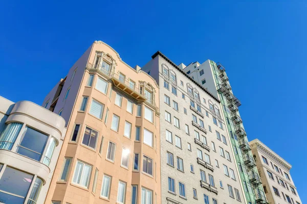 Low rise, mid rise, and high rise apartment buildings in a low angle view at San Francisco, CA. Facade of apartment buildings with different heights and exterior against the clear sky background.