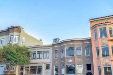 Victorian style adjacent apartments at San Francisco, California. There are two small buildings in the middle of two taller apartments with bay windows against the sky background.