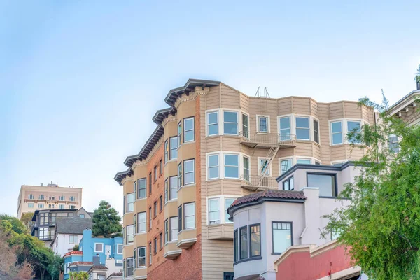 Low-rise residential buildings on a sloped suburbs of San Francisco, CA. Row of buildings with single-family houses and apartment buildings with emergency stairs.