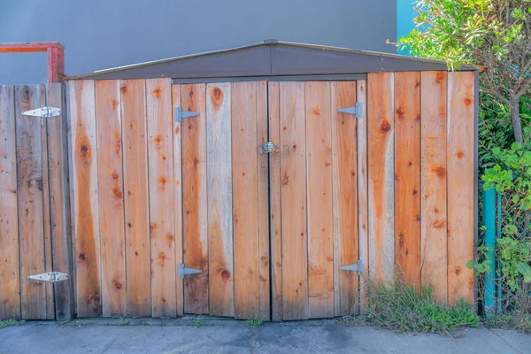 Tool shed with wood planks walls and double door in San Francisco, California. Exterior of a shed with side-hinged double doors against the wall and plants on the side and back.