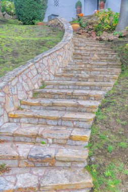 Curved concrete outdoor stairs with stone steps and wall- San Francisco, California. Staircase leading to a building entrance with potted plants.