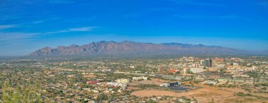 Top view of residential and commercial buildings at Tucson, Arizona. Panoramic view of a city near the mountains against the blue sky at the background.