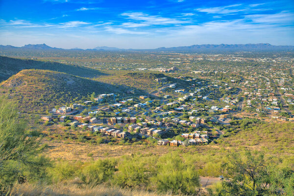 View of a suburban neighborhood from above in Tucscon, Arizona. Neighborhood near the hills and mountains against the sky at the background.