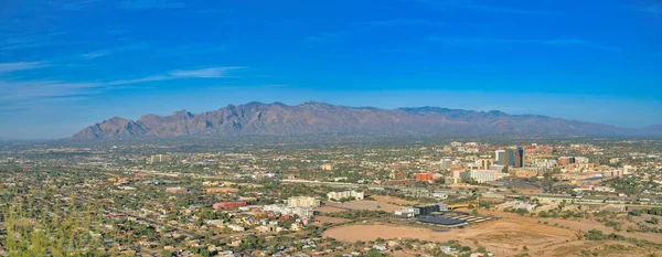 Top view of residential and commercial buildings at Tucson, Arizona. Panoramic view of a city near the mountains against the blue sky at the background.